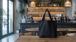 © piyawat - Modern Cafe Scene: Black Tote Bag on Wooden Table with Blurred Background of Spacious, Bright, and Airy Interior.