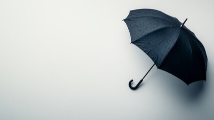 Poster - Close-up of a black umbrella with a curved handle placed on a white surface, highlighting its elegance and minimalistic style with ample copy space available