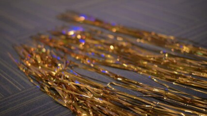Poster - Golden metallic tinsel strands spread across textured surface, creating shiny, glittering, and festive decoration perfect for celebrations and adding