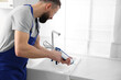 © New Africa - Worker with caulking gun sealing kitchen sink indoors