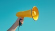 © Nice Seven - A person holds a bright yellow megaphone against a clear blue sky, symbolizing communication and amplification of voice.