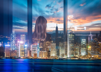 Poster - A woman looks out at the Hong Kong cityscape at night using a double exposure effect. City lights illuminate the skyline and harbor view.