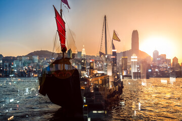 Poster - Hong Kong's iconic junk boat sailing against a vibrant sunset cityscape, enhanced with a double exposure technique for a unique layered view.