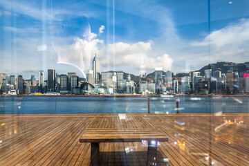 Aufkleber - A double exposure captures Hong Kong's vibrant skyline, blending city buildings with a wooden deck and reflective glass surface. The view shows water, sky, and urban architecture.