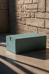 Poster - box positioned on a sunlit floor next to a textured wall in a modern interior space