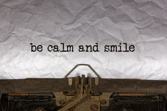 be calm and smile close up of a phrase being typed and centered on a sheet of paper on an old vintage mechanical typewriter.