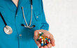 © Svetlana Verbitskaya - Health professional holds various pills and capsules while wearing a stethoscope