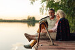 © Zamrznuti tonovi - Senior couple relaxing by lake at sunset, enjoying retirement together