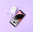 © New Africa - Mobile phone with open music player app, earphones and case on light violet background, top view