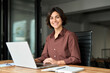 © insta_photos - Portrait of confident businesswoman leader in her 30s at work desk. Smiling Hispanic young woman entrepreneur, happy female executive manager looking at camera sitting at work with laptop.