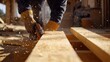 © Irybka - A construction worker sanding wooden beams at a building site. Featuring craftsmanship and precision
