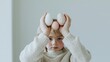 © Kan - 03041409 20 A pastel-colored editorial image with a bunny-eared child framed by eggs and soft sun rays