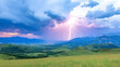 © Nadiyah - Dramatic lightning strike over vibrant green valley and mountain range during a colorful sunset