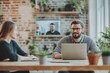 © Isuru - Man smiles while working on laptop with colleague in modern office, video call in background.