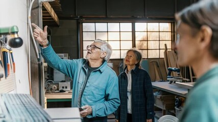 Poster - Senior engineers engage in a collaborative discussion, examining a project in a well equipped workshop. Natural light from large windows enhances the industrial setting