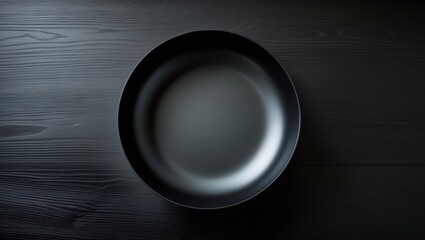 Poster - On a dark wooden surface, a top view of a black vacant round bowl.