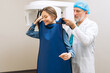 © Maria Vitkovska - Male doctor helping for woman putting protective gown for x-ray procedure