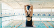 © peopleimages.com - Swimming pool, sports and back of woman stretching for workout, training and exercise for race event. Fitness, warm up and swimmer in gym for practice, challenge and competition for performance