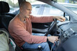 © KONSTANTIN SHISHKIN - Senior man starting car engine while holding steering wheel