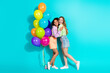 © deagreez - Two cheerful young women with colorful balloons standing against a teal background, expressing friendship