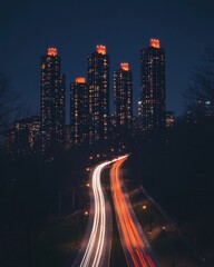 Poster - Urban nightscape with illuminated skyscrapers and vibrant light trails on winding road creating a dynamic and captivating cityscape scene from elevated view