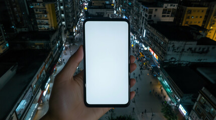 Poster - Smartphone held over city street at night with blank screen for mockup. Mobile phone in hand against the backdrop of city buildings and street with people at night