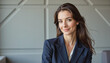 © f_bossa - Modern portrait headshot of a friendly ceo executive business worker: A professional woman with long, dark hair smiles confidently at the camera while wearing a navy blue blazer and a white top.