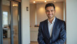© f_bossa - Modern portrait headshot of a friendly ceo executive business worker: A smiling young man in a dark suit leans against a doorway, radiating confidence and professionalism.
