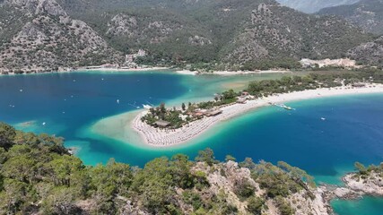 Wall Mural - Drone view of Oludeniz Beach surrounded by blue ocean and forested terrain on a sunny day in Turkey