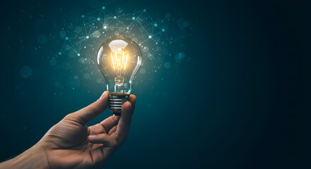 Poster - Hand Holding Glowing Light Bulb Against Dark Blue Background Idea Innovation
