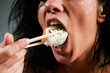 © Volodymyr - Sushi in woman mouth. Sexy woman eating sushi with chopsticks. Model eat sashimi. Sensual bite of sushi. Female tasting nigiri. Lunch at Japanese restaurant. Desire for delicious sushi. Asian food.