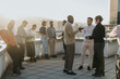 © qunica.com - A group of business colleagues engage in a brainstorming session on a high-rise balcony, fostering teamwork and innovative solutions under the warm sunlight. A setting for creative ideas and