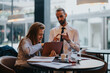 © qunica.com - Two colleagues are engaged in a discussion while using a tablet and documents in a contemporary workplace, showing teamwork and professional interaction.