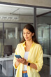 © Stock 4 You - Vertical portrait of latin hispanic woman working on smartphone standing in office for e commerce shopping or studying. Young indian girl using cell phone mobile application for work business chat
