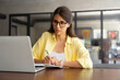 © Stock 4 You - Focused young female woman student watching webinar video conference online for studying. Latin hispanic girl in casual clothes and eyeglasses learning business lessons writing notes sitting in office