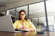 © Stock 4 You - Focused young female woman student watching webinar video online for studying. Latin hispanic girl in casual clothes, eyeglasses learning business lessons writing notes sitting in office. Copy space