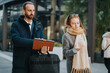 © qunica.com - Two colleagues are engaged in a conversation while walking outside during a cold day. The image portrays a professional interaction, showcasing teamwork and collaboration amidst the urban winter