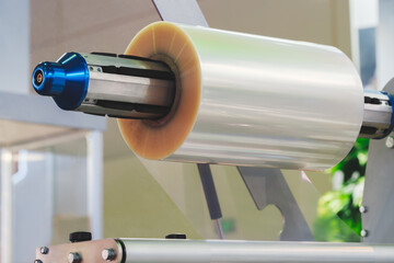 Poster - Automatic polyethylene plastic bag production machine with lighting effect. Close-up of the roller of the plastic bag production machine in the light blue scene. product packaging concept.