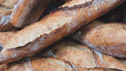 Poster - A stack of bread loaves with a few of them being slightly burnt. The bread is brown and has a crispy texture