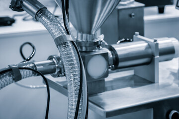 Poster - A machine with a white tube attached to it. The tube is connected to a machine that is making something