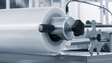Poster - Automatic polyethylene plastic bag production machine with lighting effect. Close-up of the roller of the plastic bag production machine in the light blue scene. product packaging concept