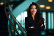© Premium - confident middle aged Asian businesswoman stands with arms crossed in modern office setting, exuding professionalism and poise