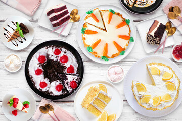Poster - Dessert table scene with a variety of cakes. Top down view over a white wood background. Black forest, lemon, carrot, red velvet, chocolate and cheesecakes.