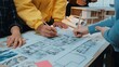 © InfiniteFlow - A collaborative atmosphere in an architecture office where multiple hands engage in sketching a detailed floor plan, surrounded by design materials and creative models. SACTR