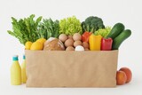 Fresh assortment of vegetables, fruits, and eggs in a basket on a clean background