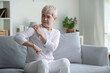 © amenic181 - Elderly Asian woman at home with shoulder pain, Senior lady feeling muscles pain attack sitting on sofa in living room.