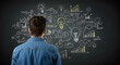 © abu - Man in Denim Shirt Viewing Lightbulb Drawing on Chalkboard Depicting Business Strategy and Innovation Ideas