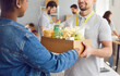 © Studio Romantic - Close up shot of a happy Caucasian man volunteer handing a food box to an African American refugee woman at a humanitarian aid center. Essence of charity, assistance, donation and help.