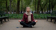 © gema - Young Middle Eastern Woman in Hijab Meditating Peacefully in a City Park.