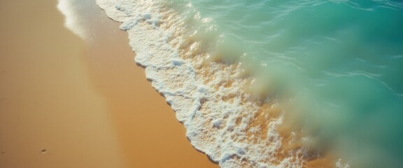Poster - Aerial view of turquoise ocean waves lapping against golden sand on a sunny day, showcasing a vibrant and serene beach landscape.